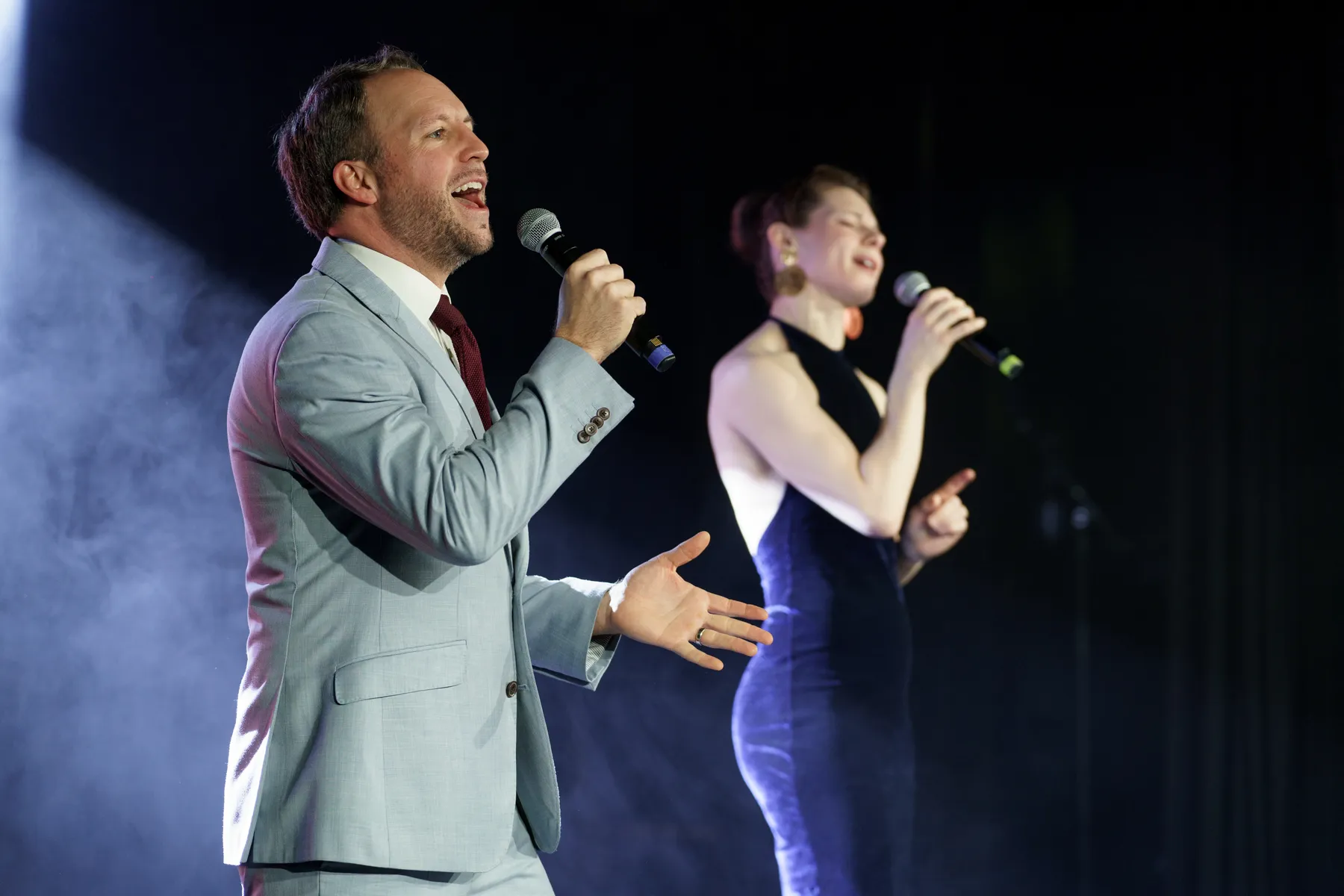 Rachel and Peter Manchester performing live under stage lighting